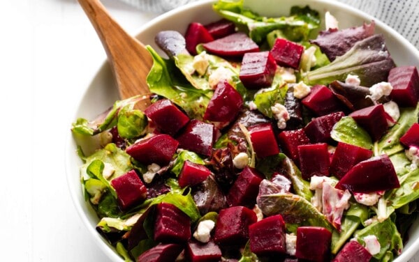 Beet salad in a bowl with a wooden spoon