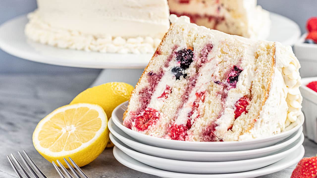 A slice of fresh berry Chantilly cake on a stack of plates