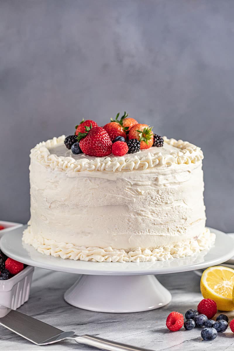 A whole fresh berry Chantilly cake on a white cake stand