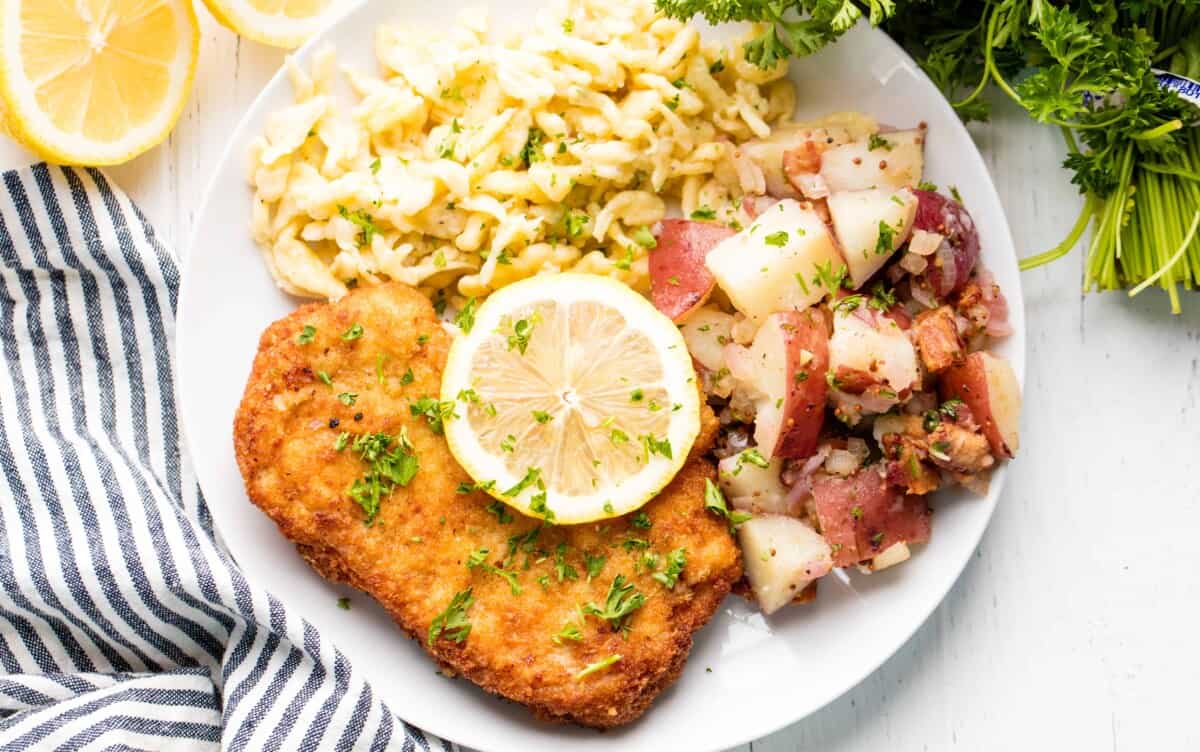 German schnitzel on a plate with spaetzle and fresh lemon