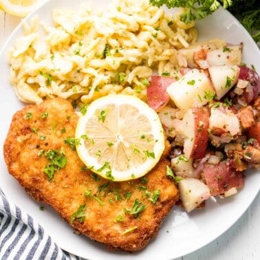 German schnitzel on a plate with spaetzle and fresh lemon