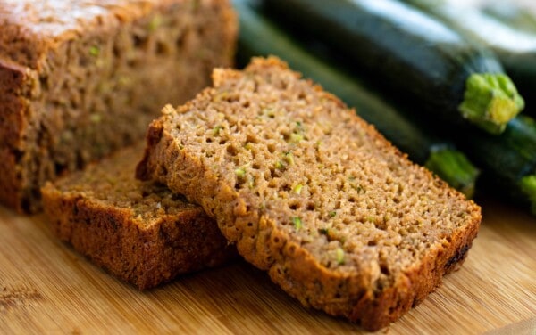 Two slices of zucchini bread sitting on a cutting board.