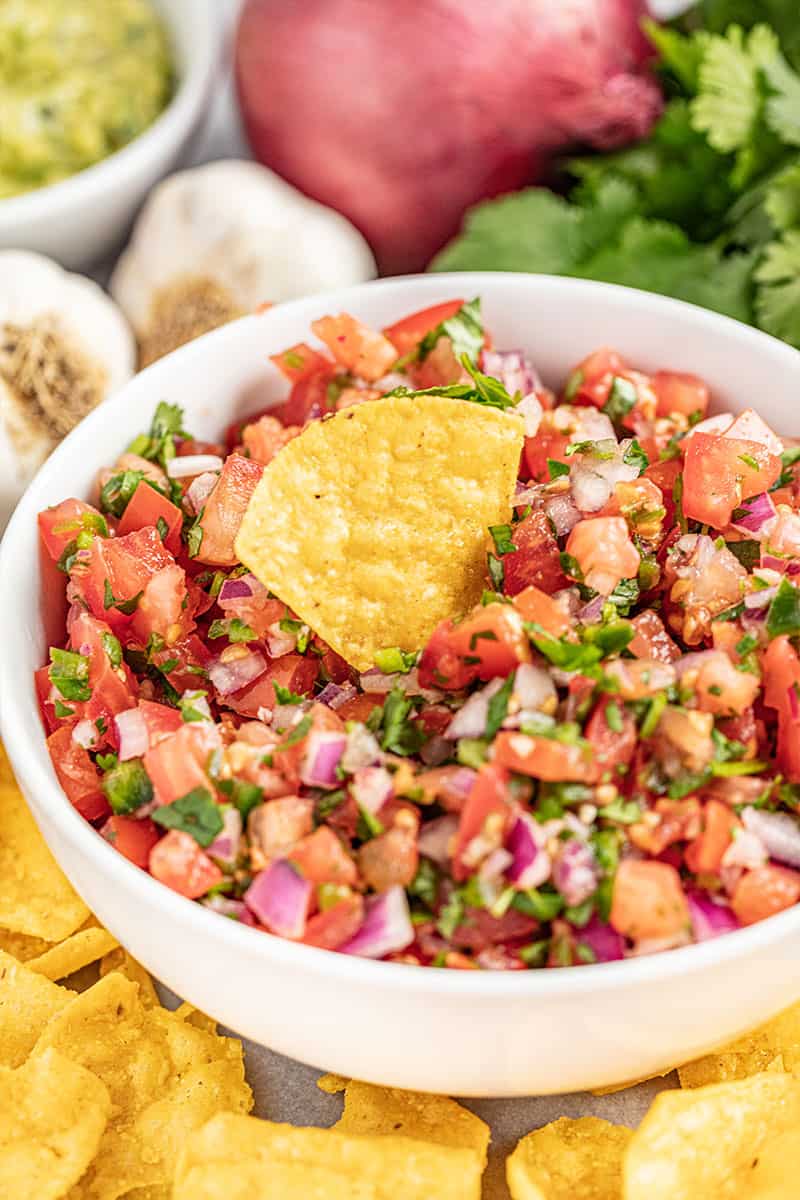 A chip sitting in a bowl of homemade salsa