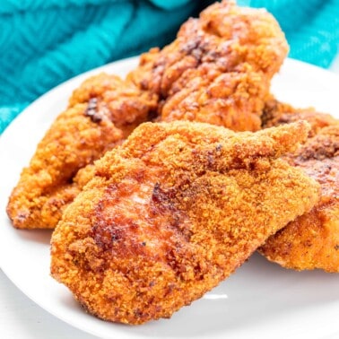 A stack of fried chicken on a white plate.