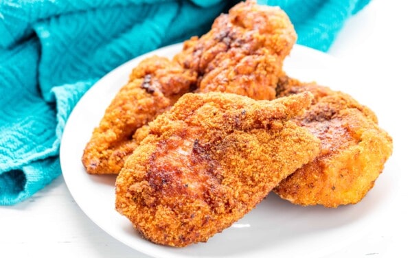 A stack of fried chicken on a white plate.