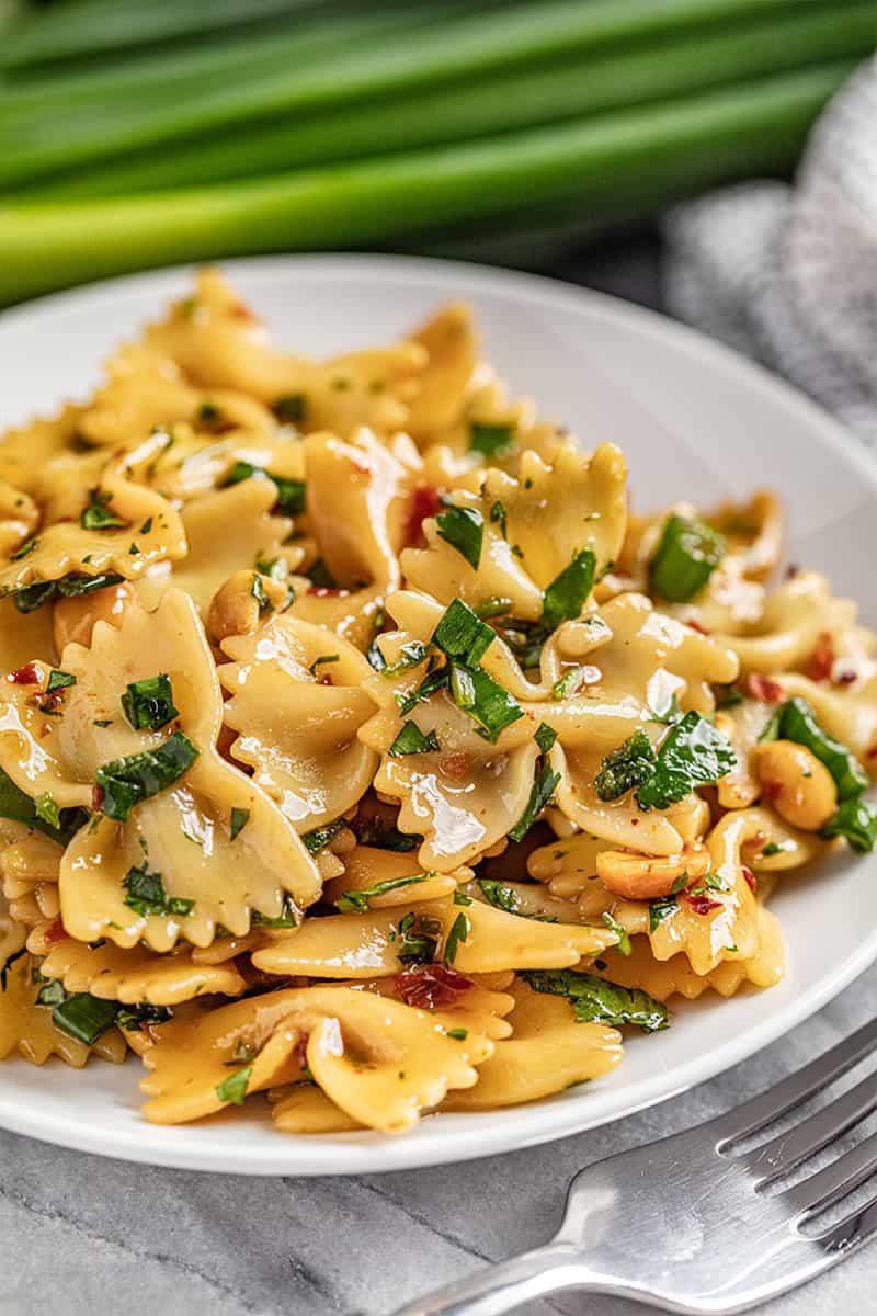 Spicy thai pasta salad on a white plate with a fork nearby