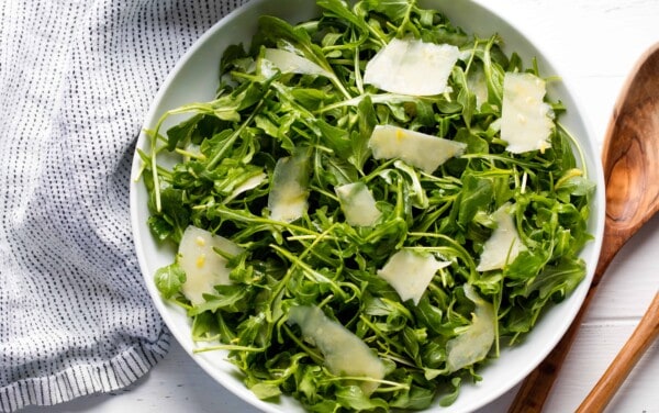 Bird's eye view of arugula salad in a white bowl.
