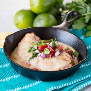 Fiesta lime chicken topped with cilantro, onions and peppers in a cast iron skillet