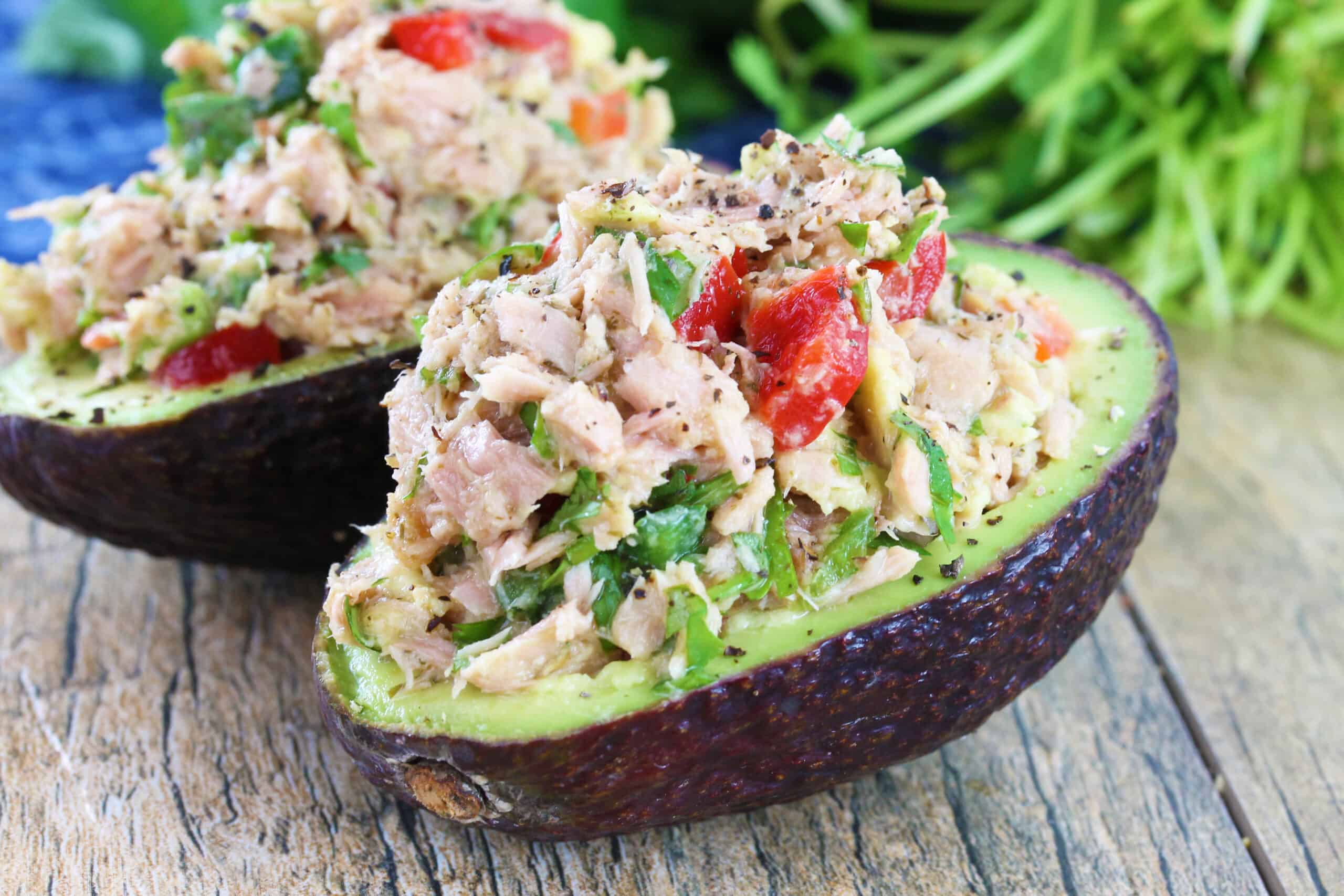 Two tuna stuffed avocados on a table top.