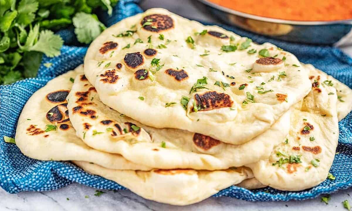 Stack of 5 pieces of naan bread on a blue towel