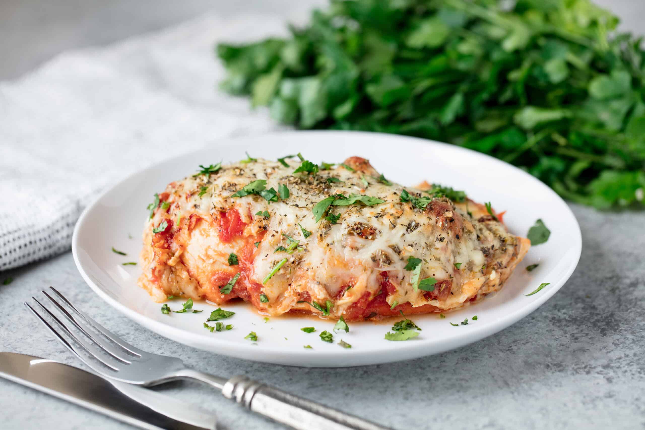 Lasagna stuffed chicken on a white plate.