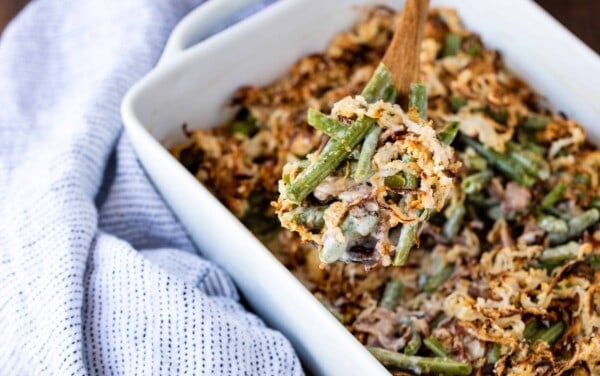 A scoop of green bean casserole above a dish of green bean casserole.