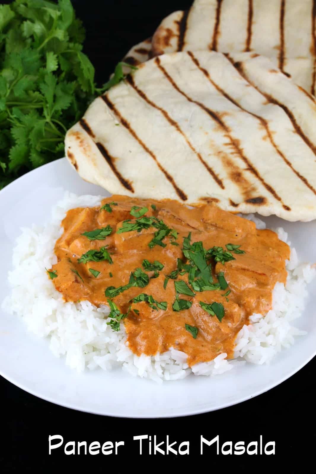 Paneer tikka masala served over white rice on a white plate with naan on the side and a text overlay that reads "Paneer Tikka Masala"