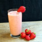 Glass of strawberry lassi garnished with fresh strawberries