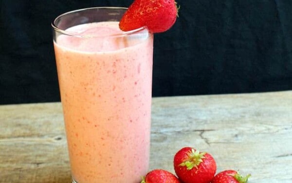 Glass of strawberry lassi garnished with fresh strawberries