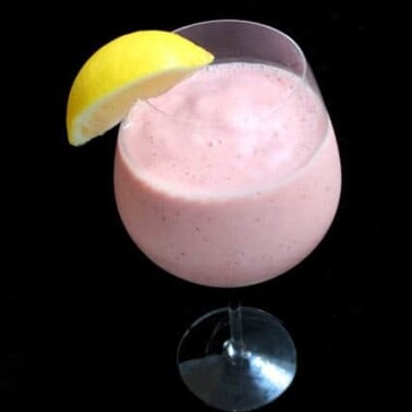 Strawberry Lemonade Smoothie in a wine glass garnished with a lemon wedge