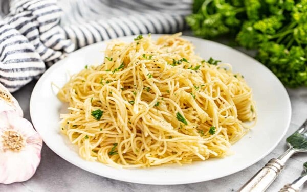 Brown butter garlic angel hair pasta served on a white plate with parsley on top