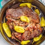 looking down into a dutch oven with a pot roast and pepperoncinis