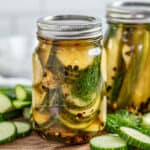 sliced pickles in a glass jar with fresh dill inside