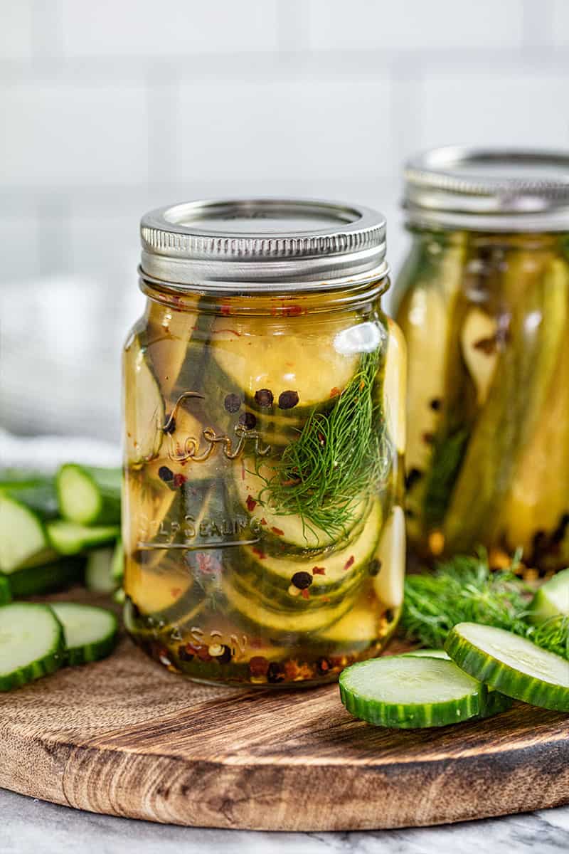 sliced pickles in a glass jar with fresh dill inside
