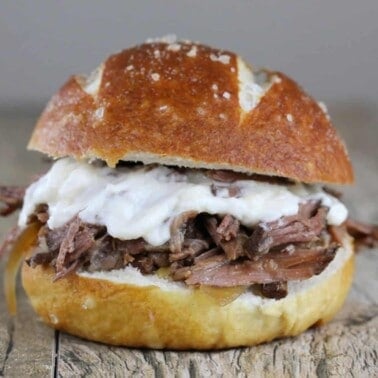 Slow Cooker Beef and horseradish sandwich with cheese on a woodentable.