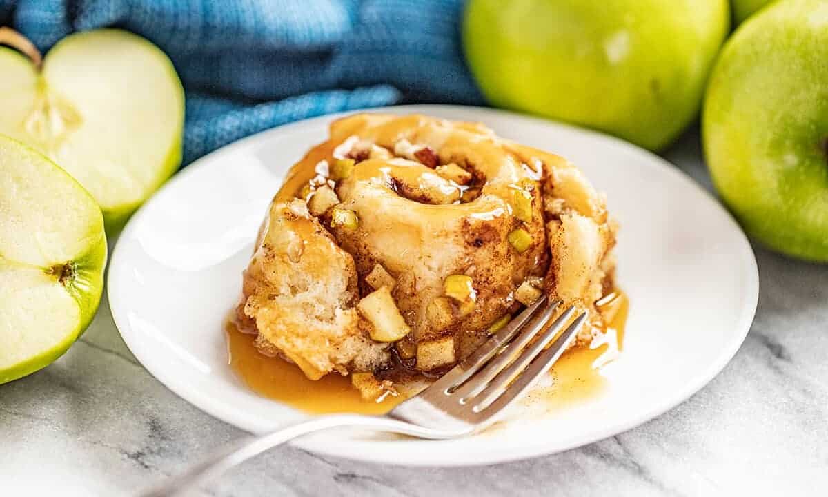 A caramel apple cinnamon roll served on a white plate