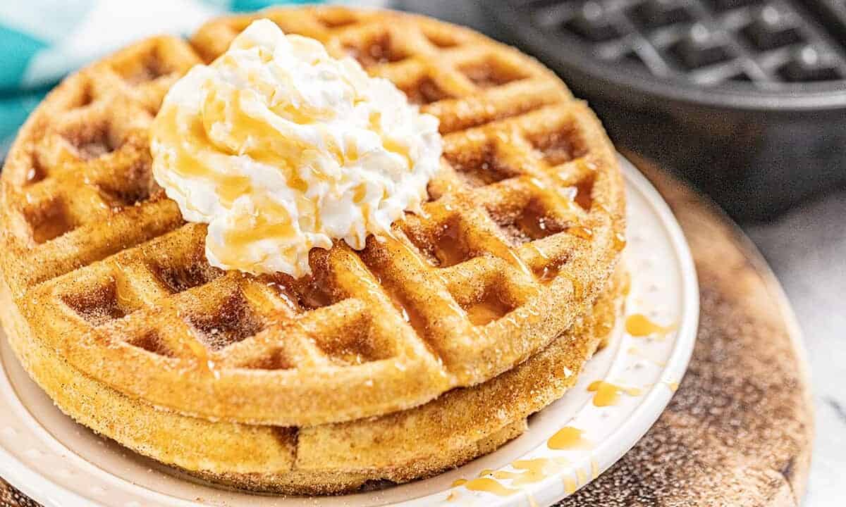 A plate of churro waffles with butter on top and drizzled with caramel