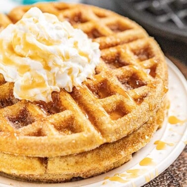 A plate of churro waffles with butter on top and drizzled with caramel