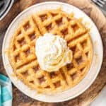 overhead view of a white plate with stacked churro waffles with whipped butter and caramel on top