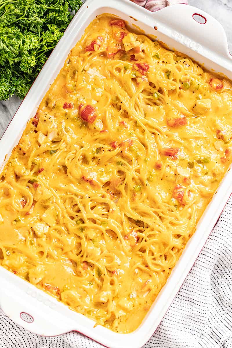 a red and white baking dish filled with cheesy chicken spaghetti