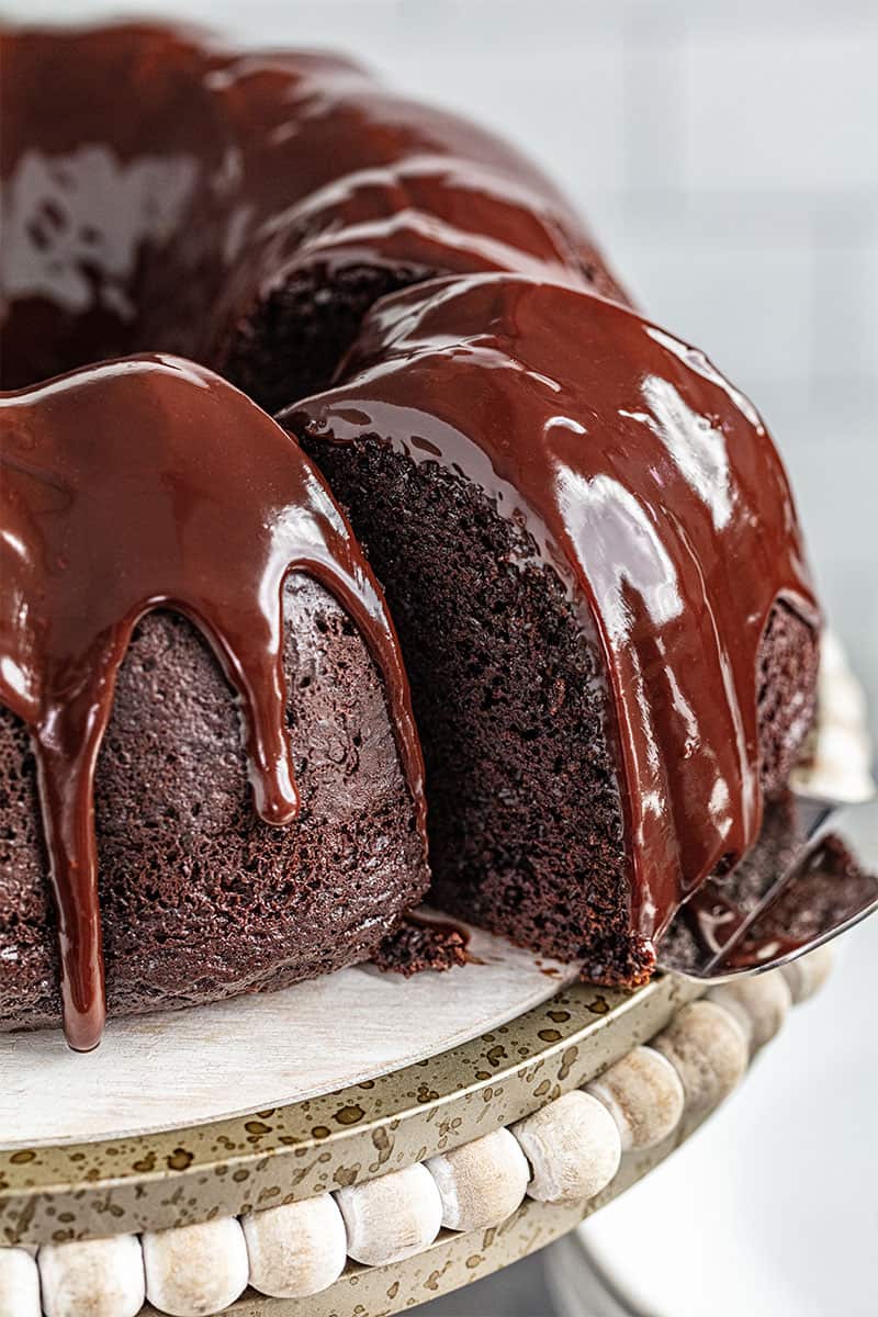 a cake server sliding a piece of chocolate bundt cake away from the rest of the cake.