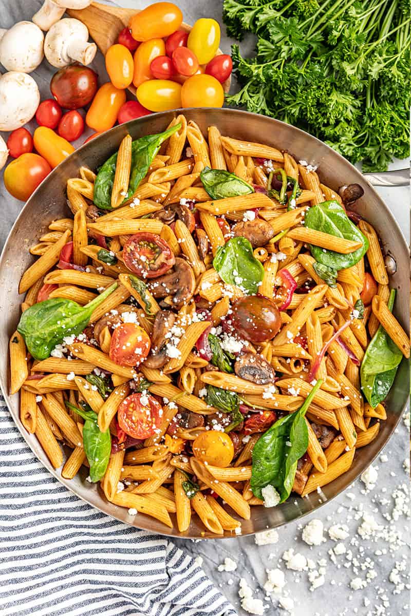 overhead view of pasta Fresca in a skillet with fresh tomatoes and mushrooms nearby