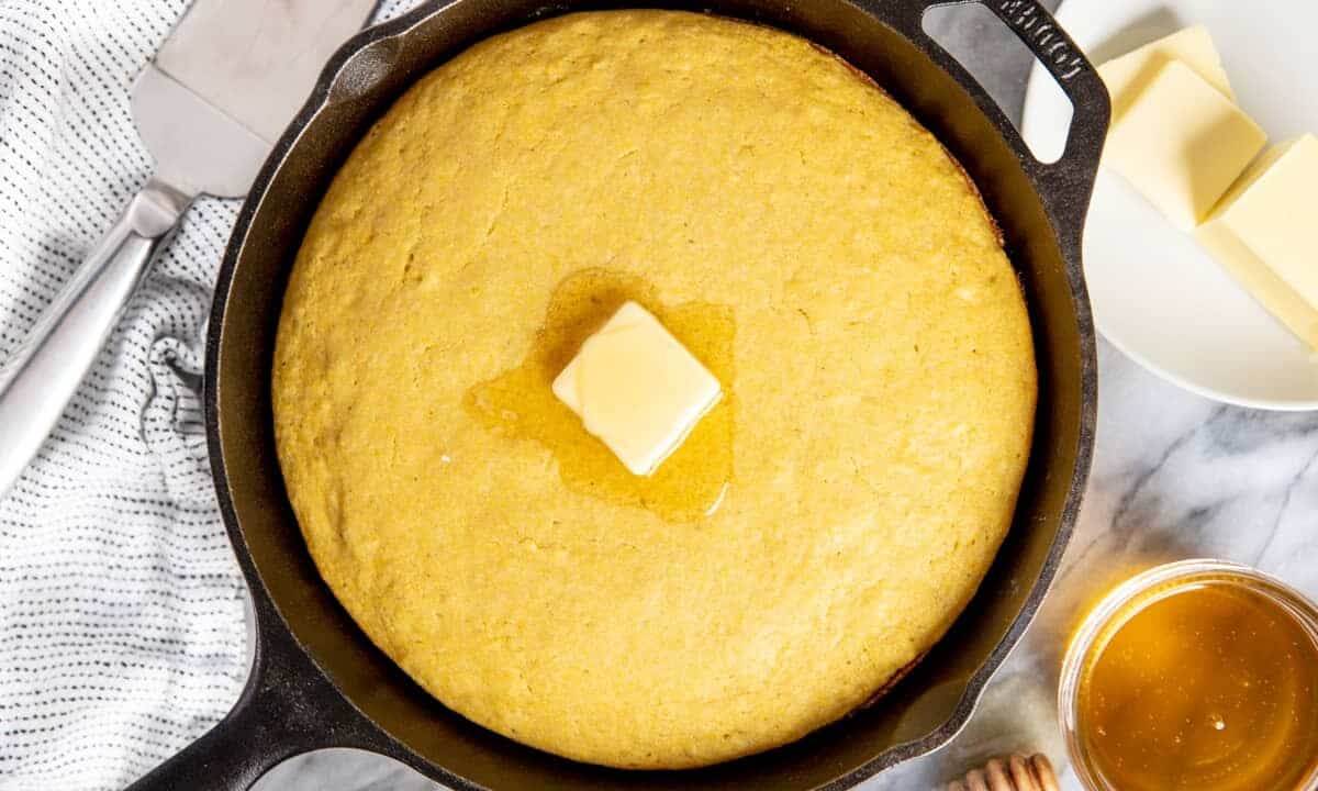 Cornbread in a skillet with a pat of butter on top