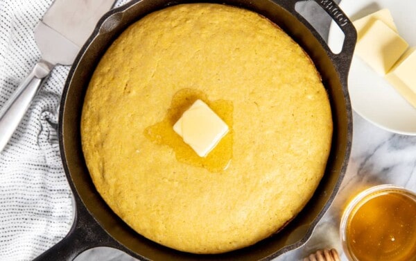 Cornbread in a skillet with a pat of butter on top