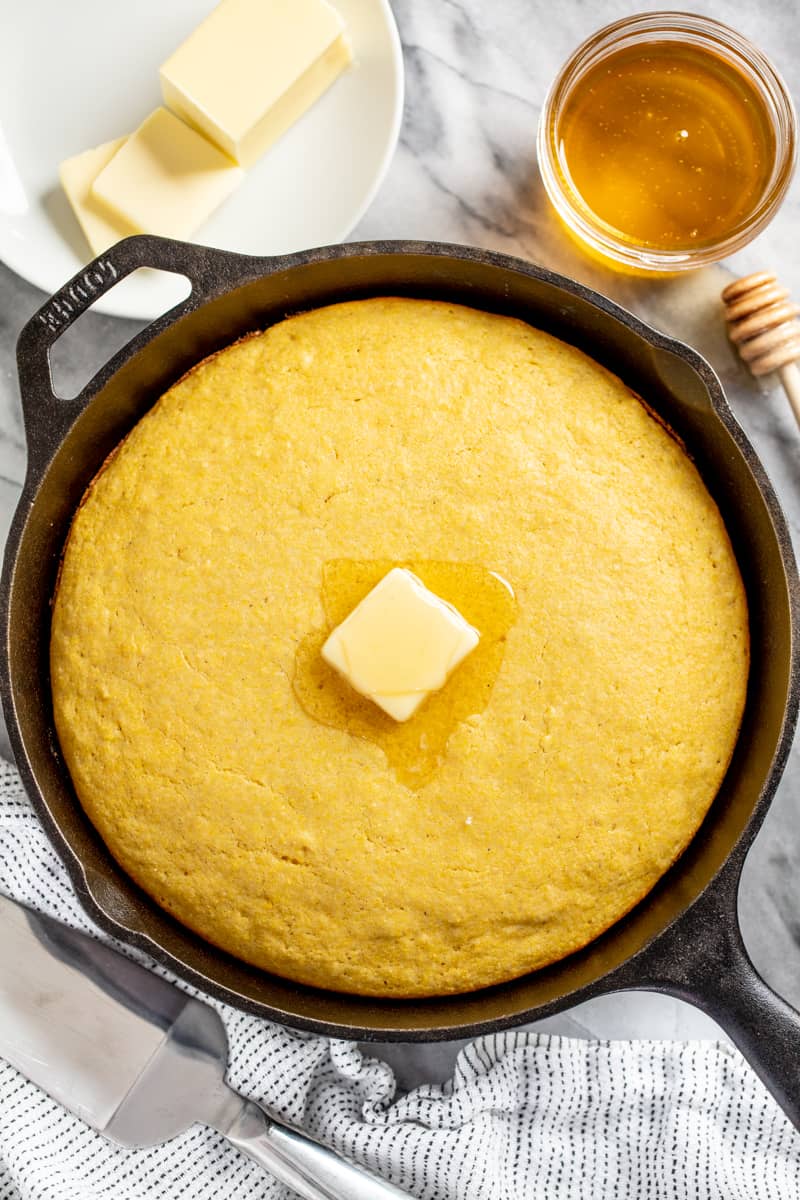 Cornbread in a skillet with a pat of butter on top