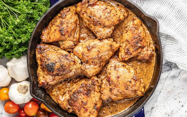A skillet full of chicken thighs in a creamy sun dried tomato sauce