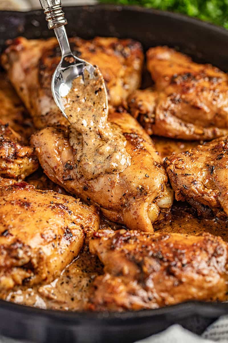 A skillet full of chicken thighs with creamy sun dried tomato sauce