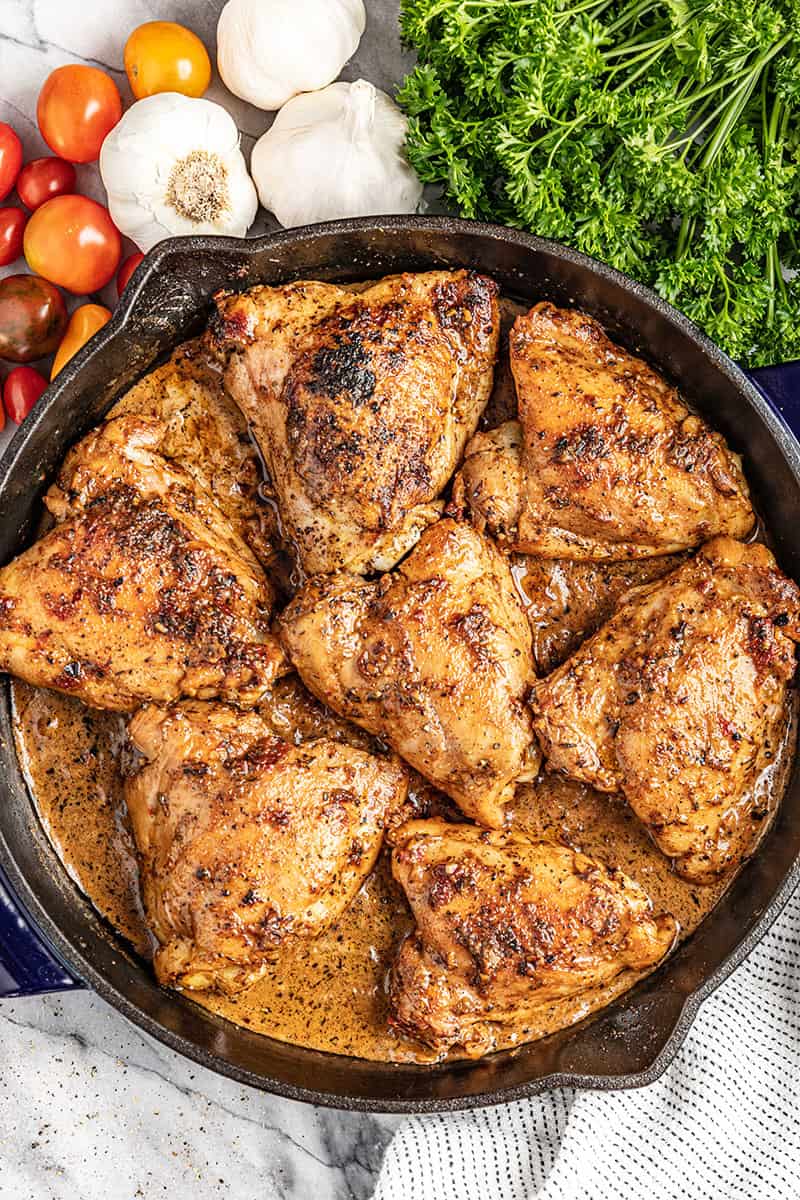 An overhead view of a cast iron skillet with cooked chicken thighs