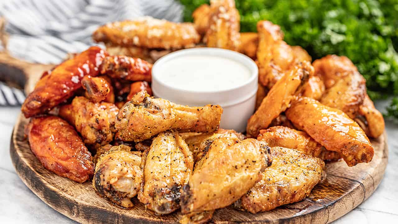 Oven baked chicken wings on a serving board with ranch dressing in the center
