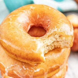 A stack of glazed donut with a bite taken out of one