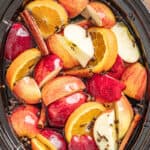 a crockpot full of apples, oranges, and spices for apple cider
