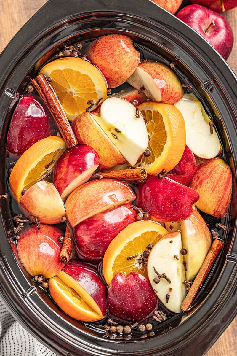 a crockpot full of apples, oranges, and spices for apple cider