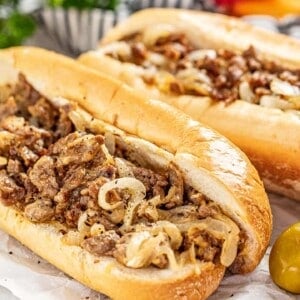 2 Philly cheesesteak sandwiches with onions on a hoagie roll