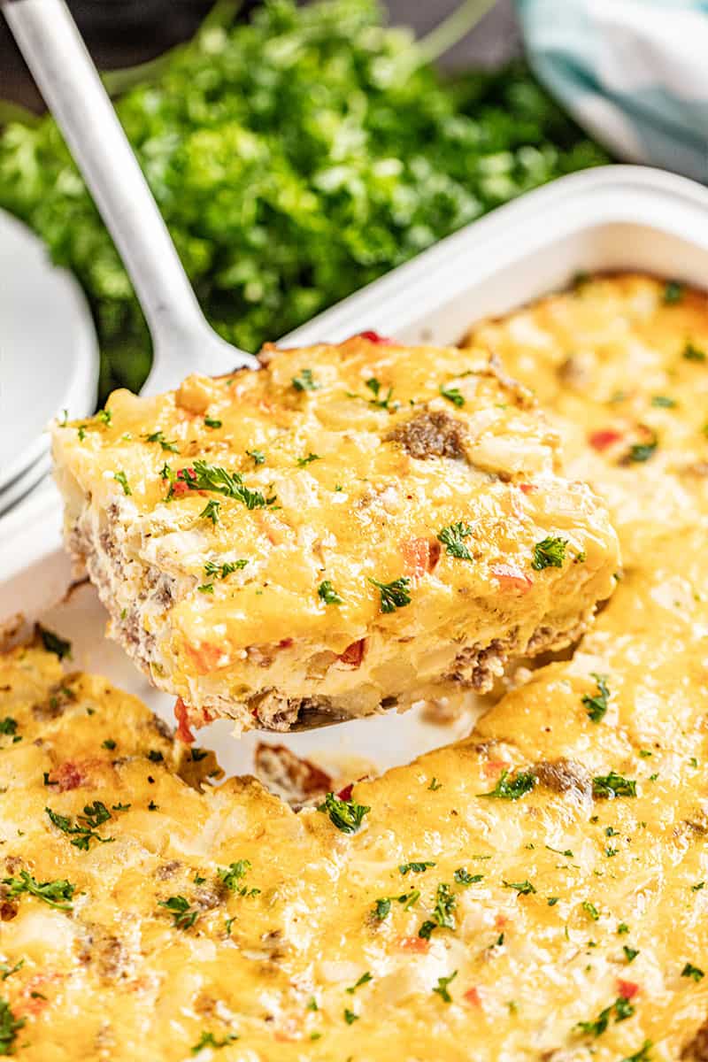 A slice of hash brown casserole being dished out of a 9x13 casserole dish.