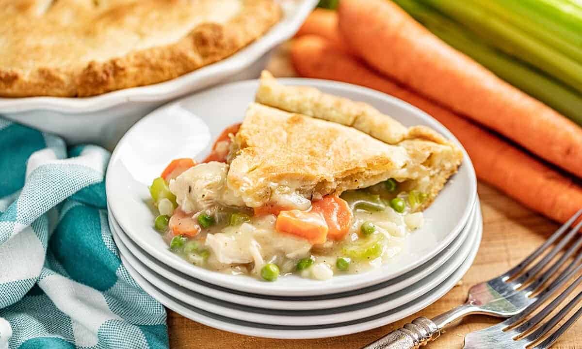 a slice of chicken pot pie on a white plate with filling oozing out.