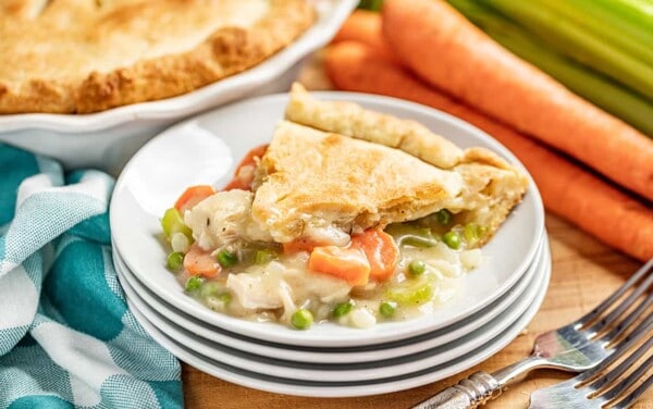 a slice of chicken pot pie on a white plate with filling oozing out.