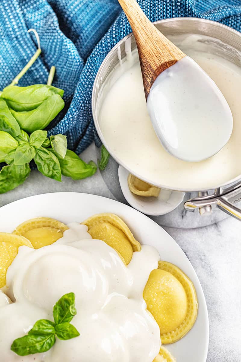 a plate of ravioli coated in béchamel sauce.