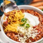 A spoon dipping into a bowl of Texas Chili.