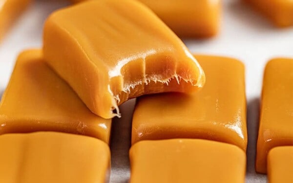A stack of caramels with one with a bite removed.