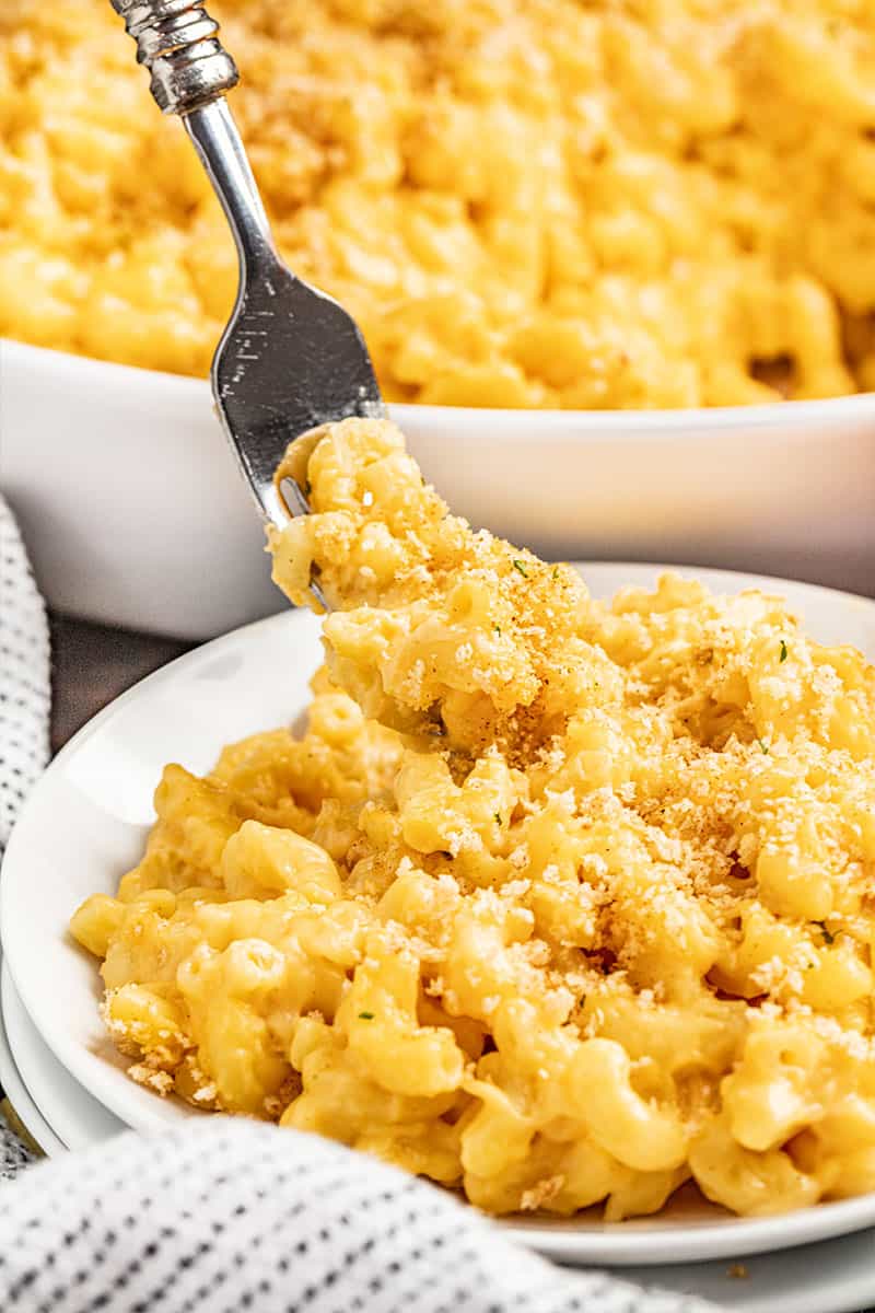 A bowl of Mac and cheese with a fork taking a bite out.